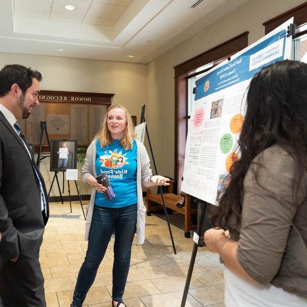 At right, Travus Burton, director for Civic Learning and Community Engagement, looks at a poster presentation from the 2019 Civic Engagement Showcase.