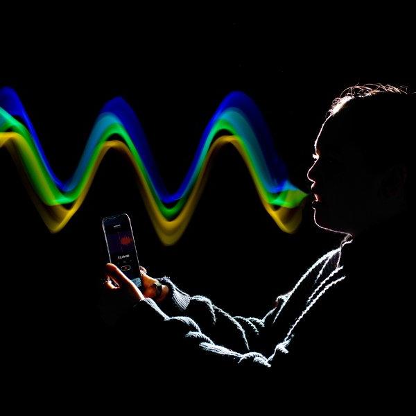 photo illustration of person holding cell phone, sound waves coming from mouth