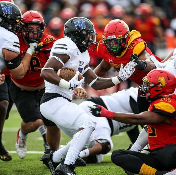 A Lakers football player tries to slip past Ferris State players.