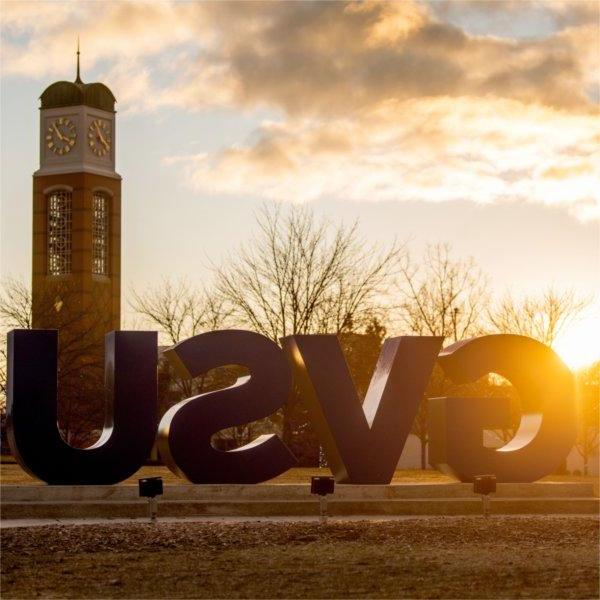 The carillon is seen at a sunrise behind the GVSU letters.